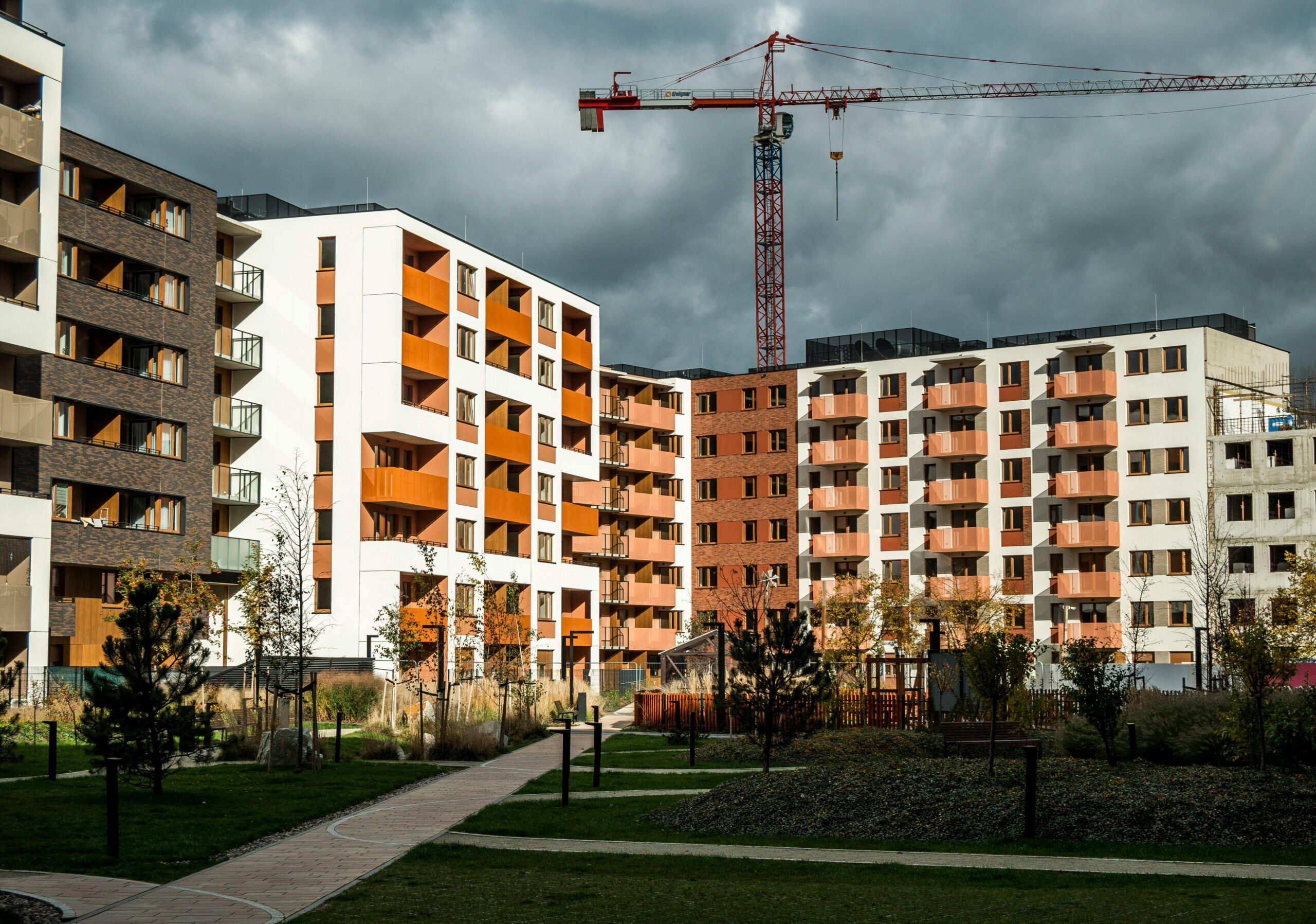 Newly built residential buildings under cloudy skies with a construction crane.